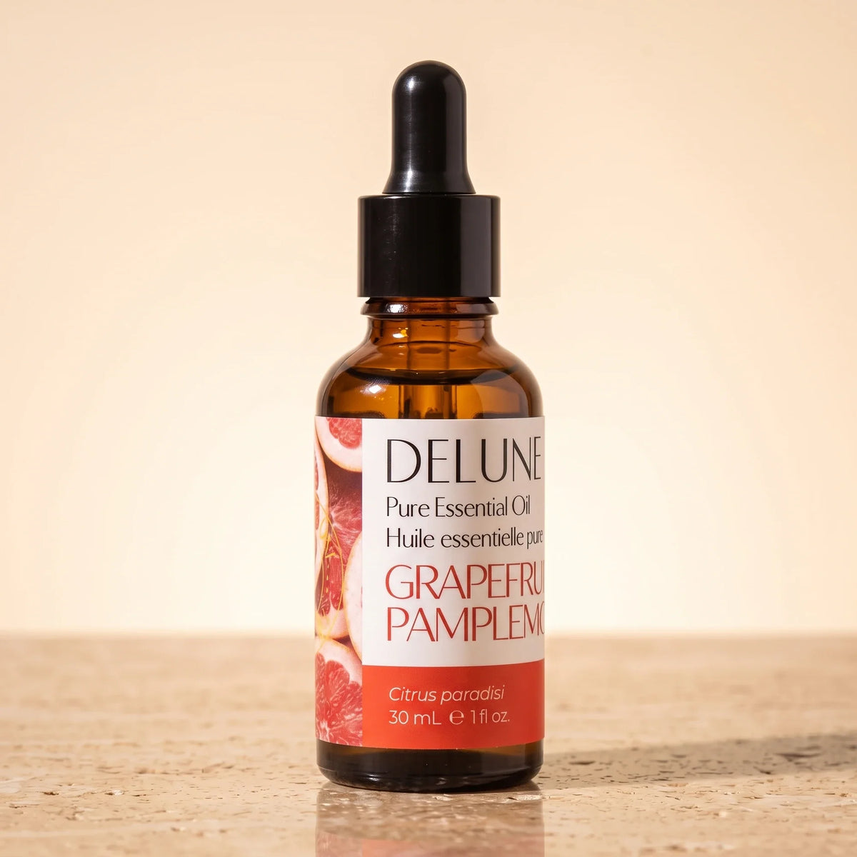 Delune Grapefruit (Pink) Pure Essential Oil, 30ml amber glass dropper bottle on warm travertine stone