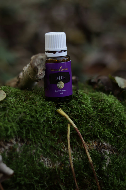 A bottle of essential oil sitting on a mossy surface
