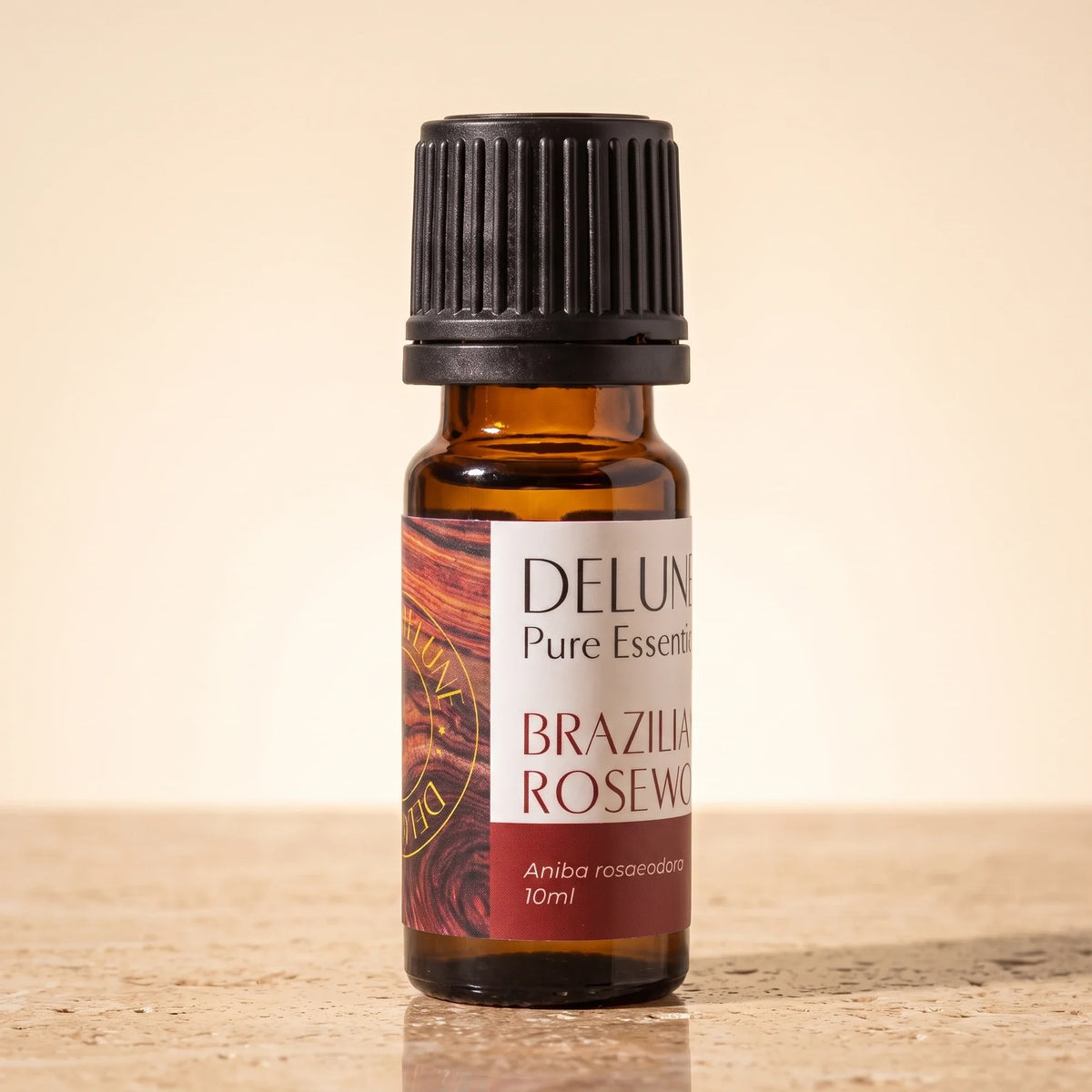 Delune Brazilian Rosewood Pure Essential Oil, 10ml amber glass bottle on warm travertine stone