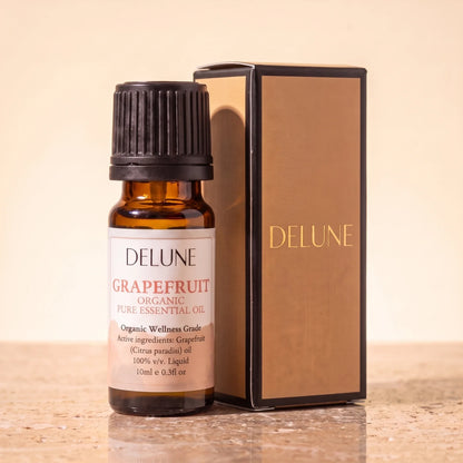 Delune Grapefruit Organic Wellness Grade Essential Oil, 10ml amber glass bottle with its gold-foil Delune gift box on warm travertine stone