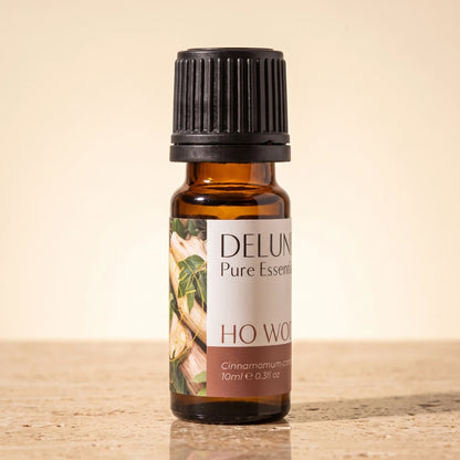 Delune Ho Wood Pure Essential Oil, 10ml amber glass bottle on warm travertine stone