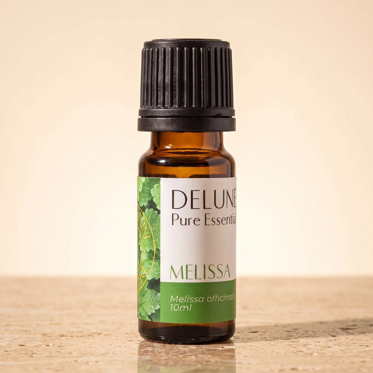 Delune Melissa Pure Essential Oil, 10ml amber glass bottle on warm travertine stone
