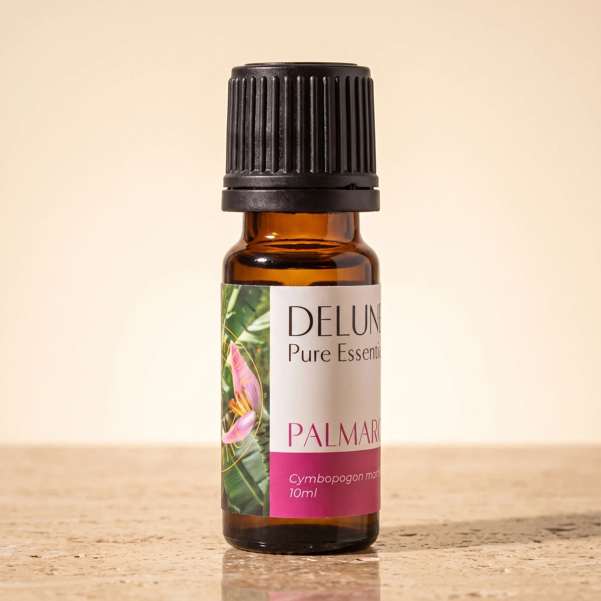 Delune Palma Rosa Pure Essential Oil, 10ml amber glass bottle on warm travertine stone