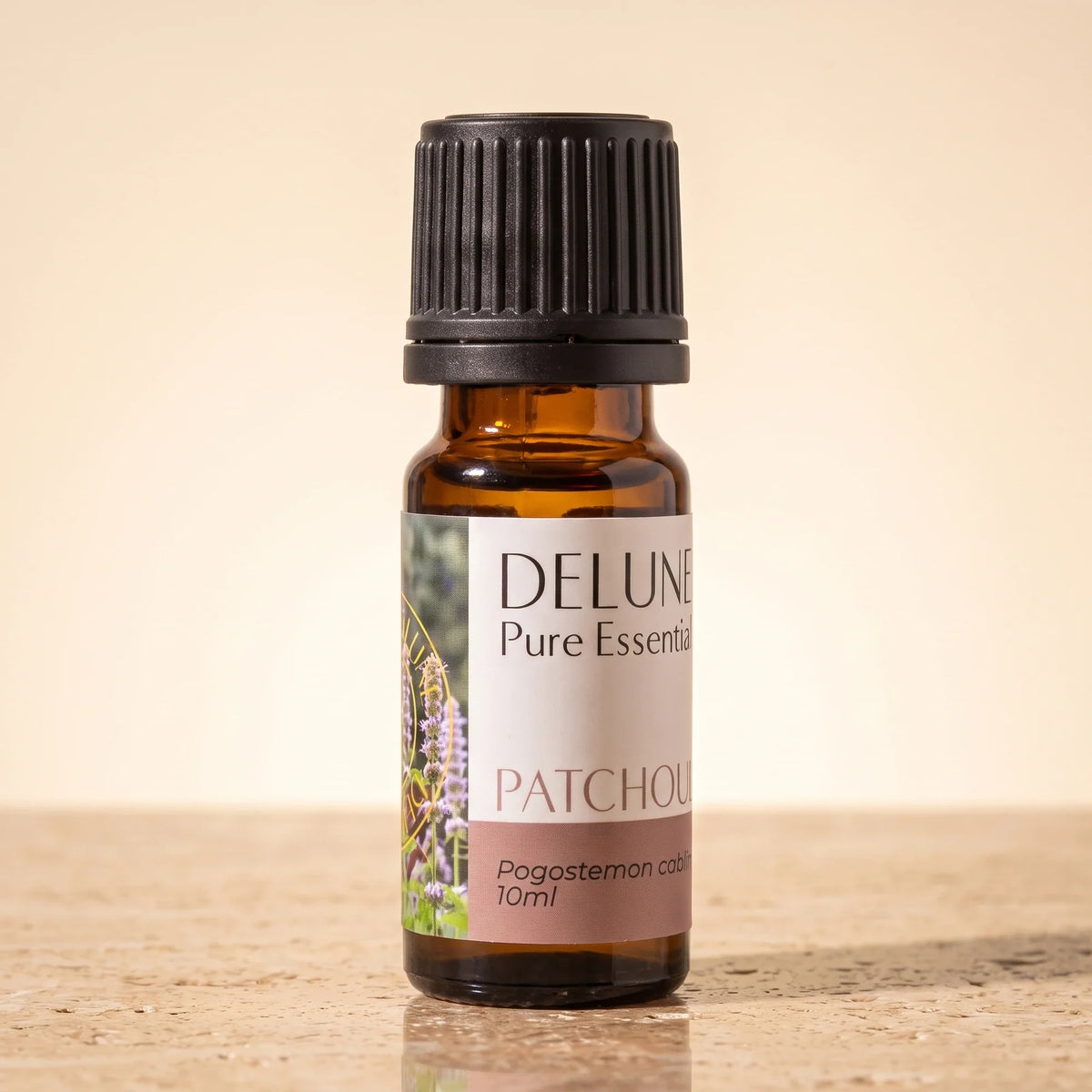 Delune Patchouli Pure Essential Oil, 10ml amber glass bottle on warm travertine stone