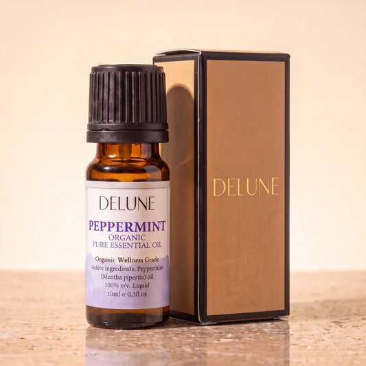 Delune Peppermint Organic Wellness Grade Essential Oil, 10ml amber glass bottle with its gold-foil Delune gift box on warm travertine stone