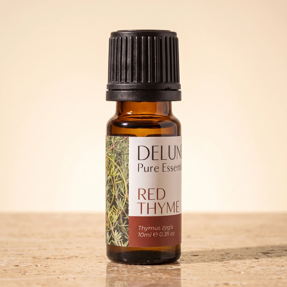 Delune Red Thyme Pure Essential Oil, 10ml amber glass bottle on warm travertine stone