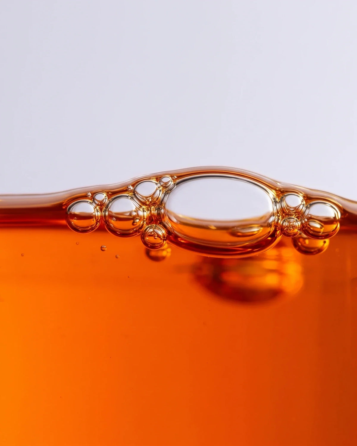 Revive 49% Sea Buckthorn Oil Serum texture: macro of vivid orange sea buckthorn oil with bubbles at the surface