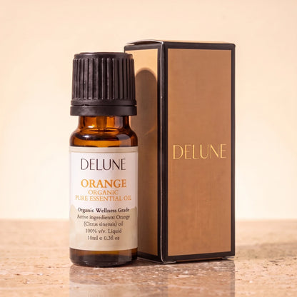 Delune Sweet Orange Organic Wellness Grade Essential Oil, 10ml amber glass bottle with its gold-foil Delune gift box on warm travertine stone