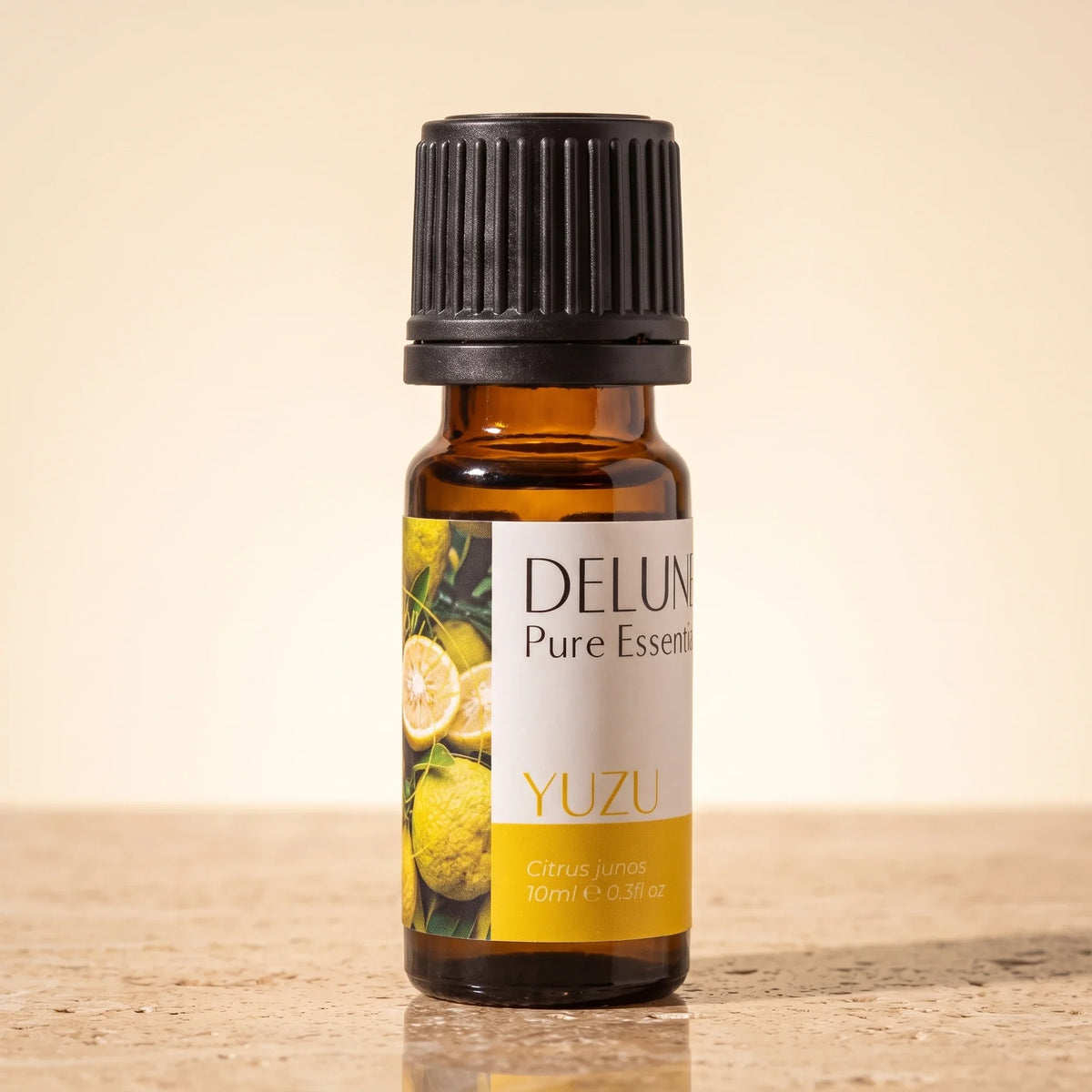Delune Yuzu Pure Essential Oil, 10ml amber glass bottle on warm travertine stone